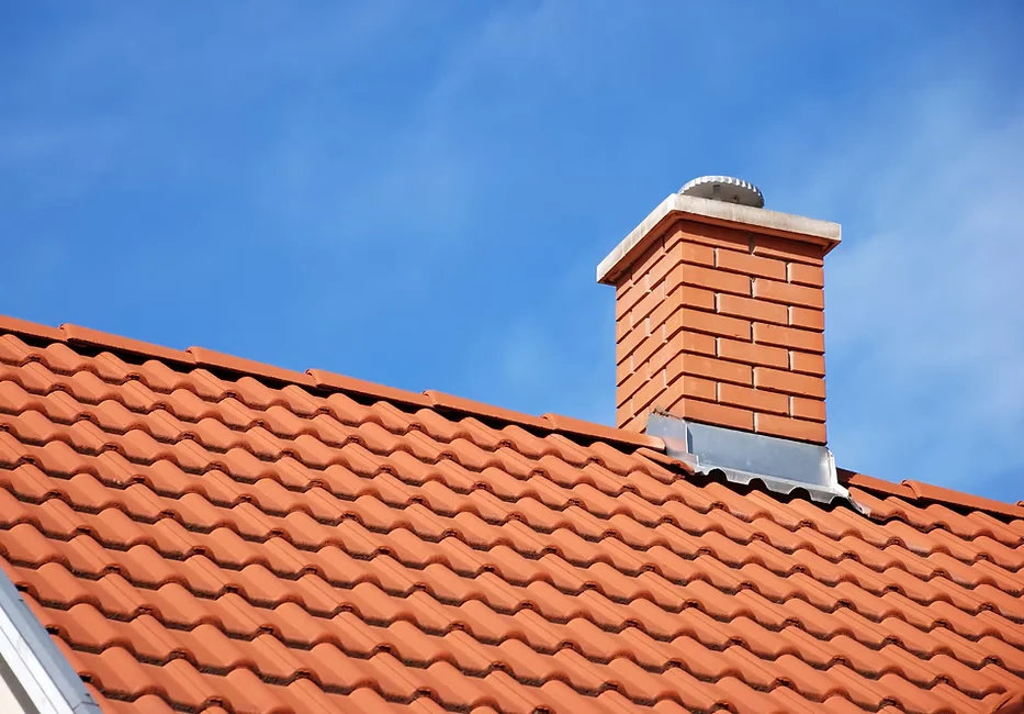 Chimney on a roof against a clear blue sky, showcasing a typical residential architecture
